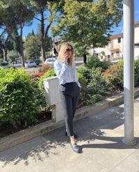 a woman is standing on a sidewalk talking on her cell phone